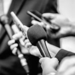 Close-up of microphones held by journalists during a press conference