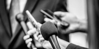 Close-up of microphones held by journalists during a press conference