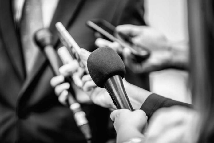 Close-up of microphones held by journalists during a press conference
