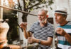 Two men engaged in a distillation process outdoors, examining a tool