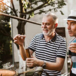 Two men engaged in a distillation process outdoors, examining a tool