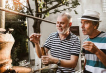 Two men engaged in a distillation process outdoors, examining a tool