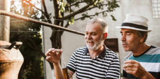 Two men engaged in a distillation process outdoors, examining a tool