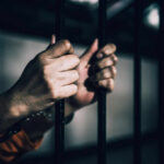 Holy Week Prisoner Releases: Vatican’s Role Questioned Hands gripping prison bars in a dimly lit environment