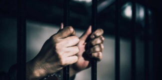 Holy Week Prisoner Releases: Vatican’s Role Questioned Hands gripping prison bars in a dimly lit environment