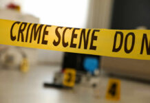 Yellow crime scene tape with evidence markers in a room