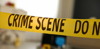 Yellow crime scene tape with evidence markers in a room