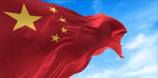 U.S. Data Centers DEPEND on Chinese Parts Waving Chinese flag with five yellow stars against a blue sky