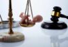 Scales of justice with a baby figurine and a gavel in the background