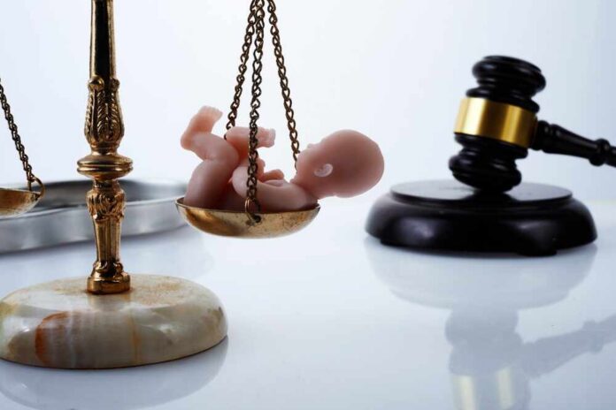 Scales of justice with a baby figurine and a gavel in the background