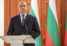 A political leader standing at a podium in front of national flags