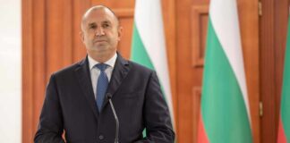 A political leader standing at a podium in front of national flags
