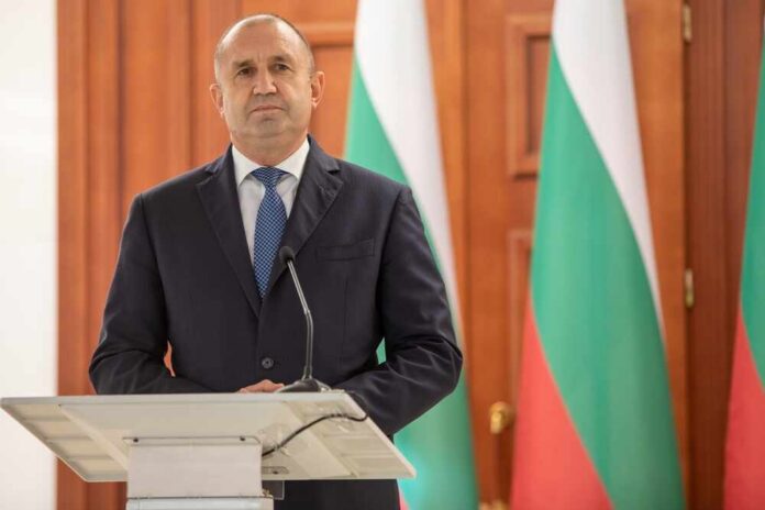A political leader standing at a podium in front of national flags