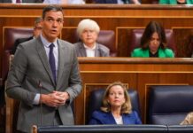 A politician delivering a speech in a government assembly with attentive audience members