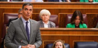 A politician delivering a speech in a government assembly with attentive audience members