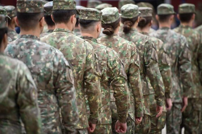 shutterstock_2376304567.jpg Line of soldiers in camouflage uniforms standing in formation