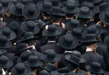 A large crowd of men wearing black hats and traditional attire, viewed from above