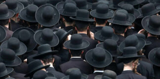 A large crowd of men wearing black hats and traditional attire, viewed from above