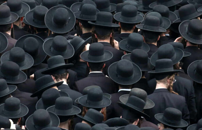 A large crowd of men wearing black hats and traditional attire, viewed from above