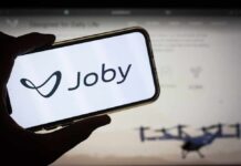 A hand holding a smartphone displaying the Joby logo