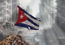 Tattered Cuban flag waving over a pile of rubble in a devastated urban landscape