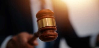 A judge's gavel being raised in a courtroom setting