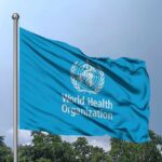 Flag of the World Health Organization waving against a blue sky