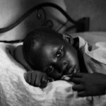 A child lying on a bed with a contemplative expression in black and white