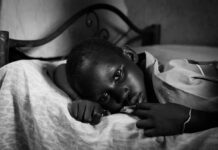 A child lying on a bed with a contemplative expression in black and white