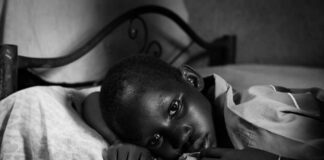 A child lying on a bed with a contemplative expression in black and white