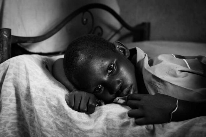 A child lying on a bed with a contemplative expression in black and white