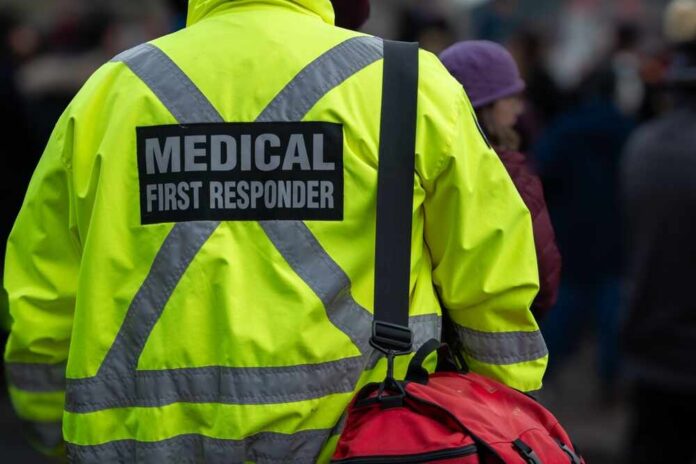 Medical first responder wearing a bright yellow jacket and carrying a red bag