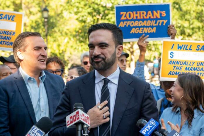 shutterstock_2686923171.jpg A politician speaking at a rally with supporters holding signs