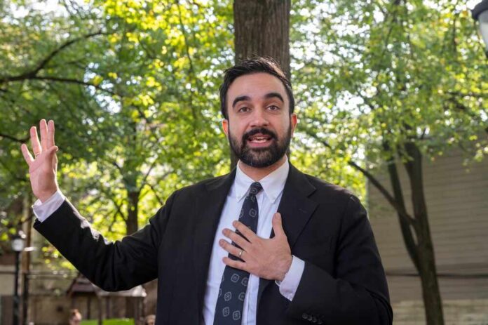 Man in a suit speaking outdoors with trees in the background