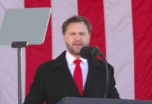Man speaking at a podium with an American flag backdrop