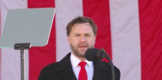 Man speaking at a podium with an American flag backdrop