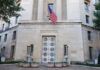 Facade of a government building featuring the American flag and decorative entrance