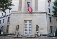 Facade of a government building featuring the American flag and decorative entrance