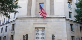 Facade of a government building featuring the American flag and decorative entrance