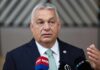 MAGA’s Last Stand in Hungary: Election Drama Unfolds A government official speaking at a press conference with microphones in front