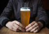 Person holding a glass of craft beer in a bar