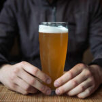 Person holding a glass of craft beer in a bar