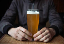 Person holding a glass of craft beer in a bar