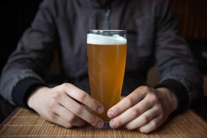 Person holding a glass of craft beer in a bar