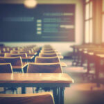 Empty classroom with wooden desks and chairs, illuminated by natural light