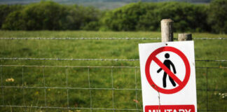 A warning sign indicating a military firing range with a no entry symbol