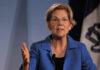 A woman in a blue blazer speaking passionately at a podium