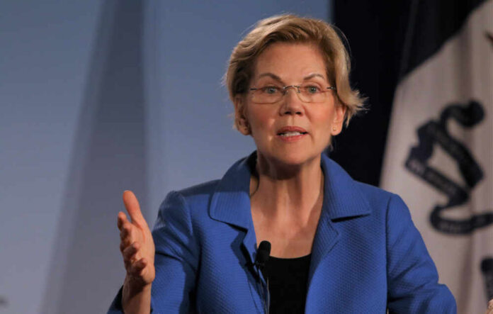 A woman in a blue blazer speaking passionately at a podium