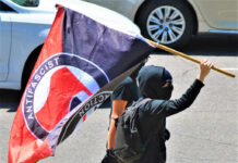 Individual holding an antifascist flag during a protest
