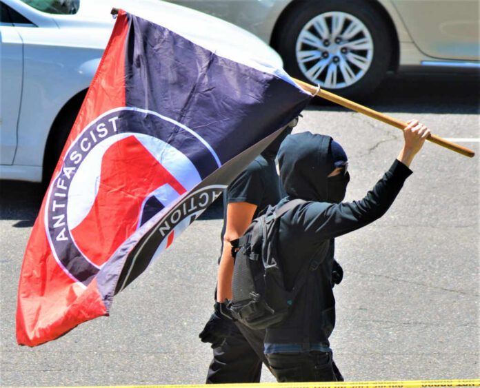 Individual holding an antifascist flag during a protest